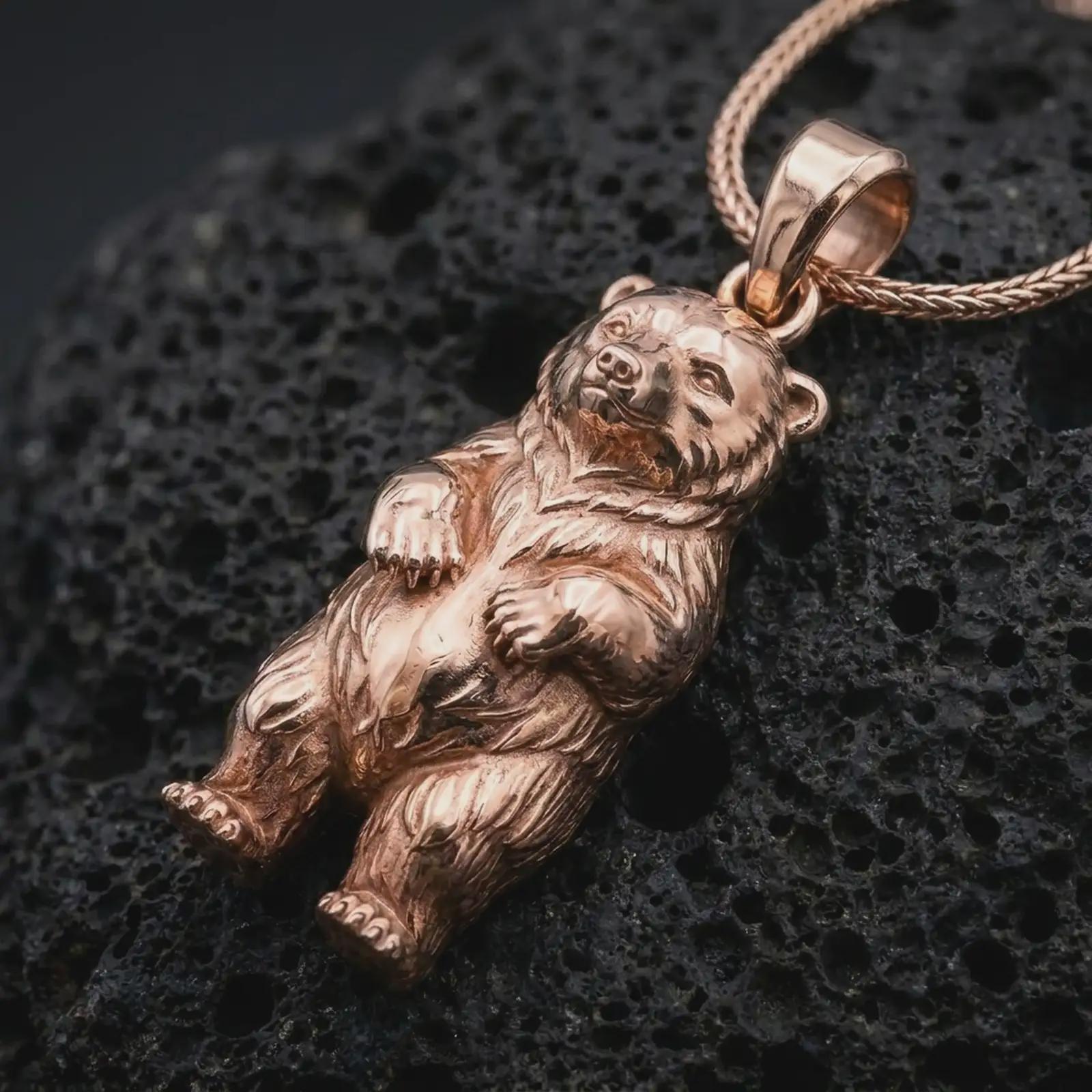Rose gold plated baby bear pendant necklace on textured volcanic rock, detailed macro product shot with soft warm reflections and sweet baby bear jewelry styling.