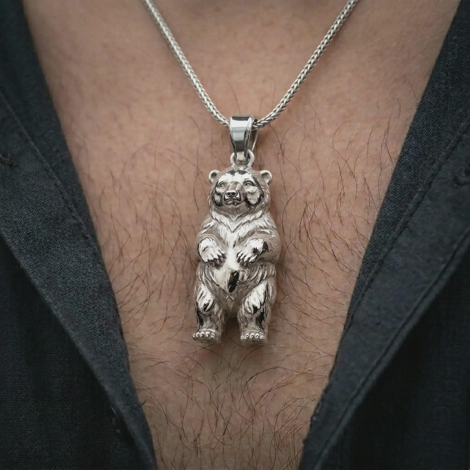 Polished silver baby bear pendant necklace worn on the chest, masculine lifestyle shot highlighting the detailed bear cub form and bright silver finish.