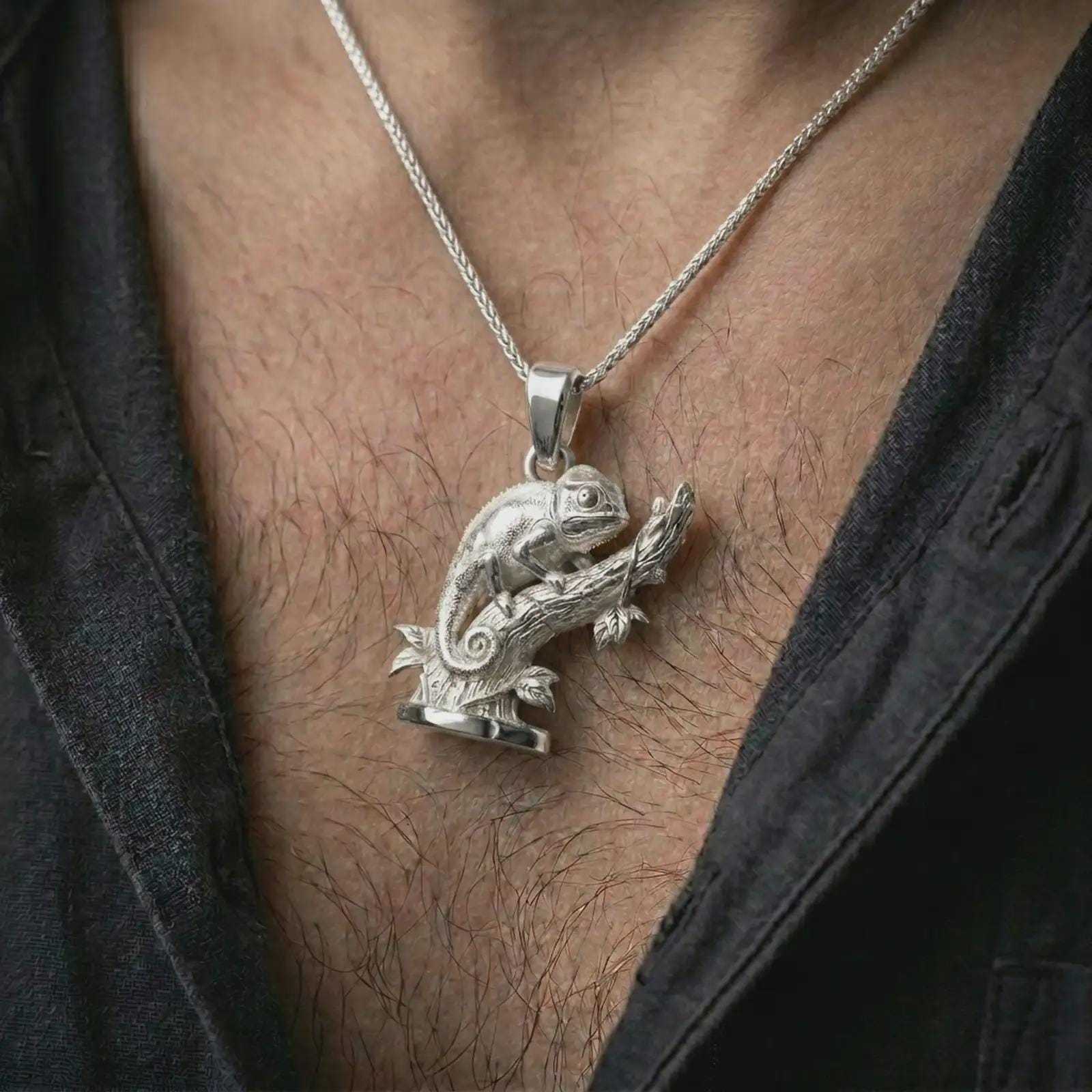 Polished silver chameleon pendant necklace worn on the chest, masculine lifestyle shot highlighting the detailed lizard form, curled tail, and bright silver finish.