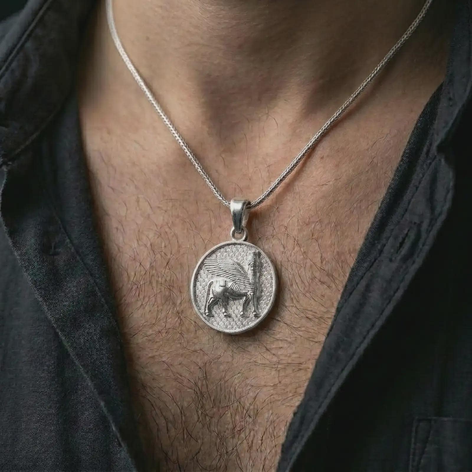 Polished silver Assyrian Lamassu pendant necklace worn on the chest, masculine lifestyle shot highlighting the winged bull relief and bright silver finish.