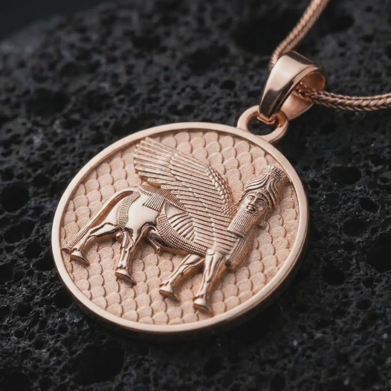 Rose gold plated Assyrian Lamassu pendant necklace on textured volcanic rock, detailed macro product shot with soft warm reflections and historic Mesopotamian design.