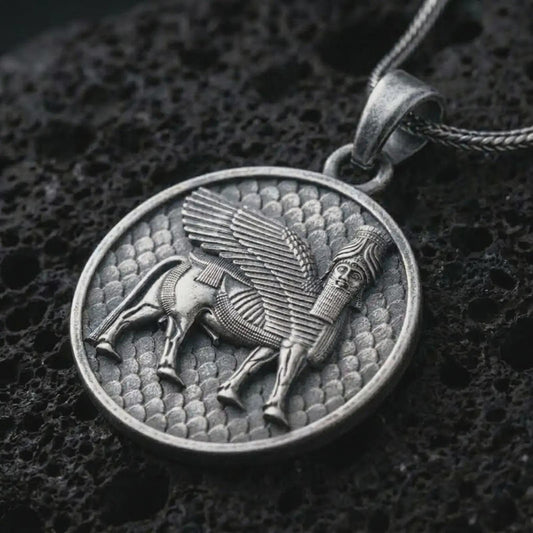 Oxidized Assyrian Lamassu pendant necklace on textured volcanic rock, close-up studio shot highlighting the winged guardian bull, ancient relief details, and antique silver contrast.