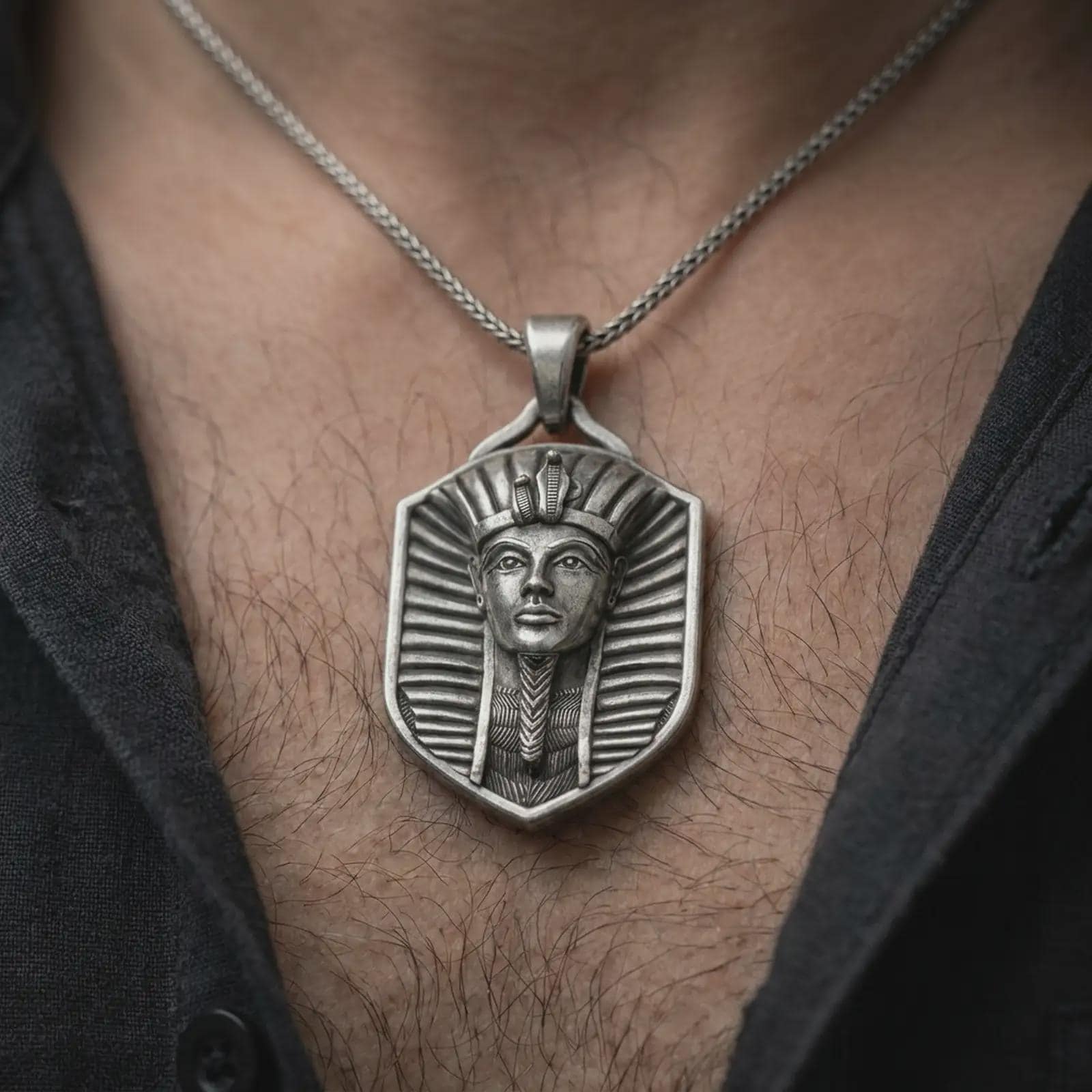 Oxidized pharaoh shield pendant necklace worn on the chest, close-up lifestyle jewelry photo showing the Egyptian amulet on a spiga chain with dark clothing.