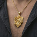 Load image into Gallery viewer, Gold plated knight shield pendant worn on the neck, macro lifestyle shot with a dark background and refined styling.
