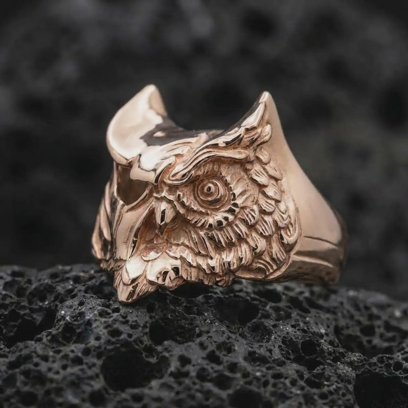 Rose gold plated owl ring photographed on volcanic rock with a luxury macro look, showing the owl’s intense gaze.