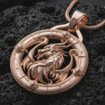 Load image into Gallery viewer, A rose gold plated dragon pendant is photographed on porous volcanic rock in a close-up studio composition with bold luxury lighting.
