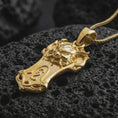 Load image into Gallery viewer, A gold plated Taurus bull pendant lies on textured volcanic rock in a dramatic studio macro shot, highlighting the bold strength symbol design.
