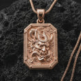 Load image into Gallery viewer, A rose gold plated Hannya mask pendant is photographed on porous volcanic rock in a close-up studio composition with bold luxury lighting.
