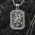 Load image into Gallery viewer, A polished silver Hannya mask pendant is displayed on black volcanic rock in a premium macro studio close-up with sharp horned mask details.
