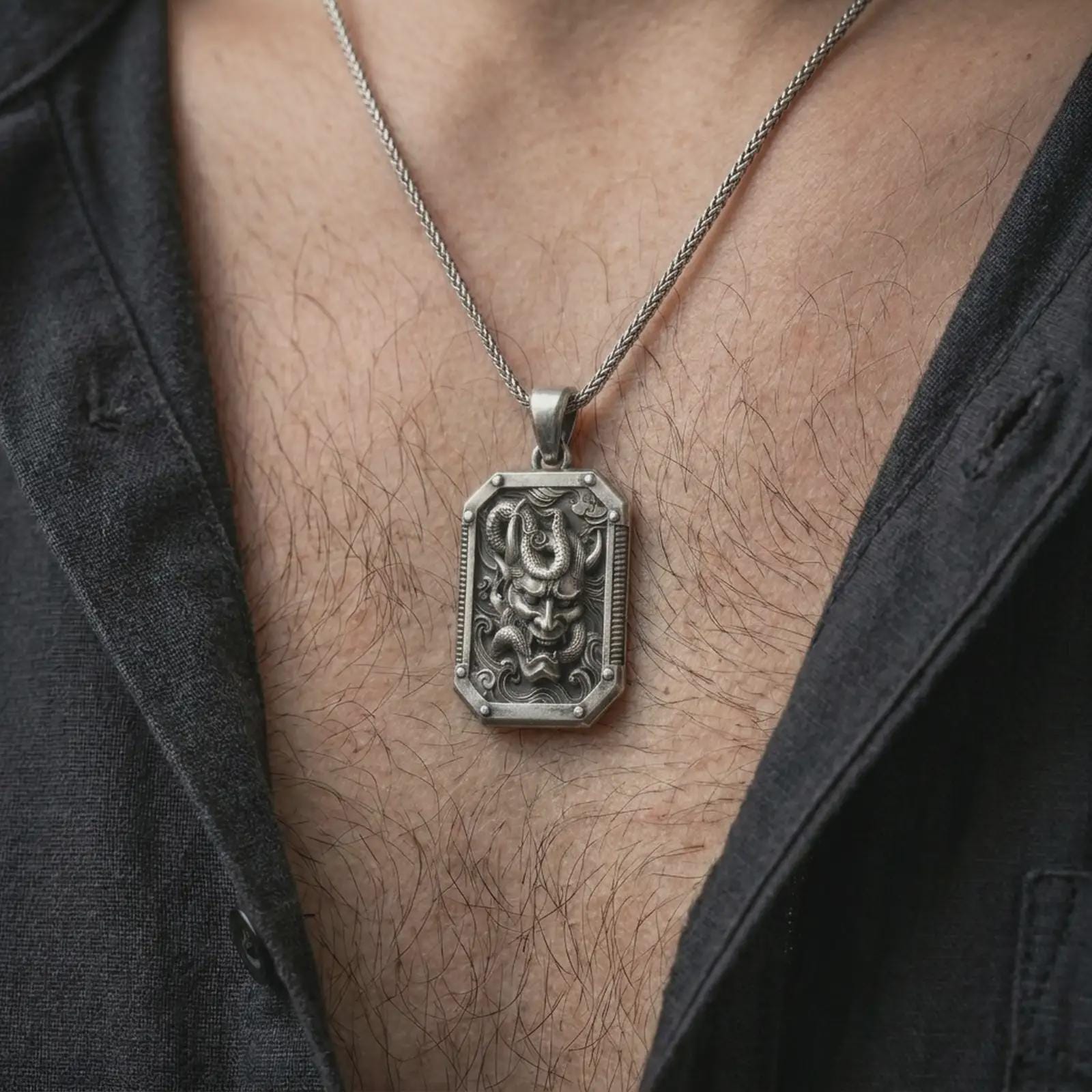 An oxidized Hannya mask pendant is worn on the neck in a close-up lifestyle shot, centered on the chest as a fierce Japanese folklore amulet.