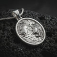 Load image into Gallery viewer, A polished silver Gemini pendant is displayed on black volcanic rock in a premium macro studio close-up with detailed twin faces and flowing botanical texture.
