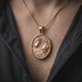 Load image into Gallery viewer, A rose gold plated Gemini pendant is worn on the neck in a close-up lifestyle composition, highlighting its duality motif and elegant floral frame.
