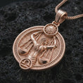 Load image into Gallery viewer, Rose gold plated Libra zodiac pendant necklace on textured volcanic rock, detailed macro product shot with soft warm reflections and symbolic zodiac styling.
