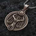 Load image into Gallery viewer, Bronze Libra zodiac pendant necklace on textured volcanic rock, close-up studio shot highlighting the scales figure, sun detail, Libra symbol, and antique silver contrast.
