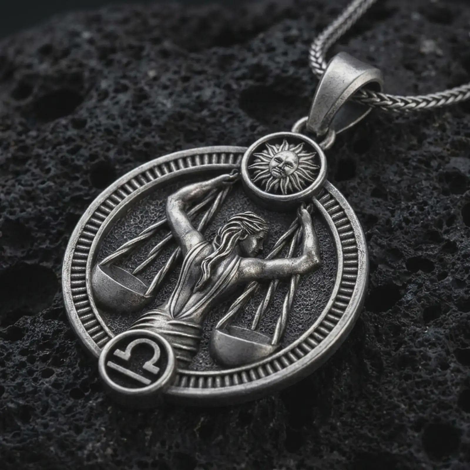 Oxidized Libra zodiac pendant necklace on textured volcanic rock, close-up studio shot highlighting the scales figure, sun detail, Libra symbol, and antique silver contrast.