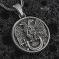 Load image into Gallery viewer, Oxidized Masonic double headed eagle pendant necklace on textured volcanic rock, close-up studio shot highlighting the 32nd degree emblem, wings, cross, motto banner, and antique silver contrast.
