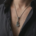 Load image into Gallery viewer, Oxidized skull guitar pendant necklace worn on the chest, close-up lifestyle jewelry photo showing the rock musician pendant on a spiga chain with dark clothing.
