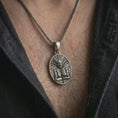 Load image into Gallery viewer, An oxidized Aztec mask pendant is worn on the neck in a close-up lifestyle shot, centered on the chest as a powerful ancient symbol necklace.
