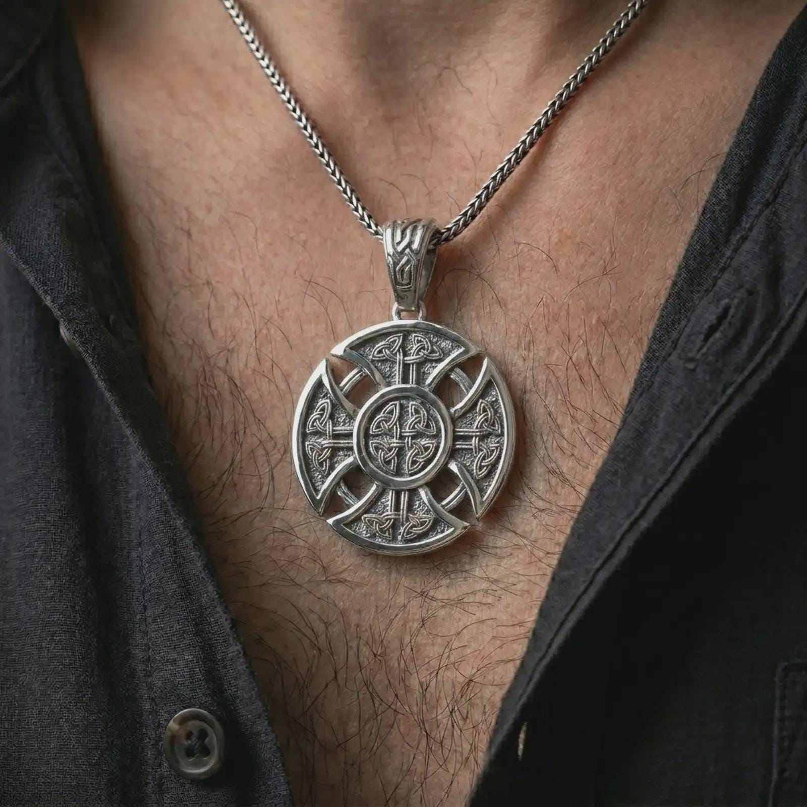 Polished silver Celtic cross pendant necklace worn on the chest, masculine lifestyle shot highlighting the bright silver finish, openwork cross shape, and detailed Celtic knots.