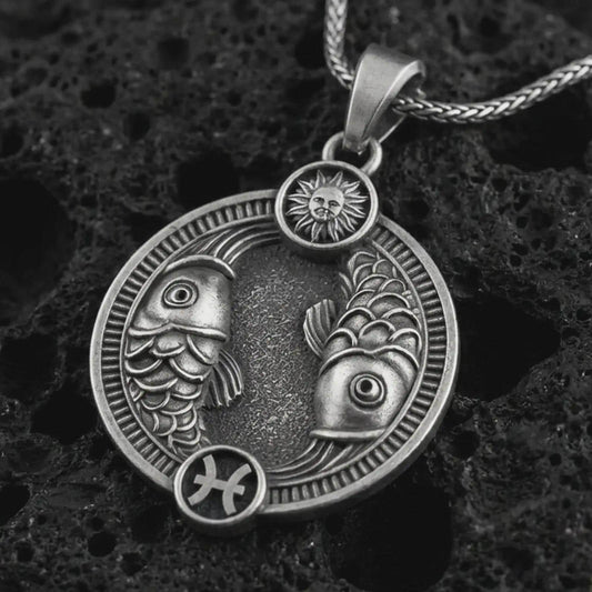 Oxidized Pisces zodiac pendant necklace on textured volcanic rock, close-up studio shot highlighting the twin fish, sun detail, Pisces symbol, and antique silver contrast.