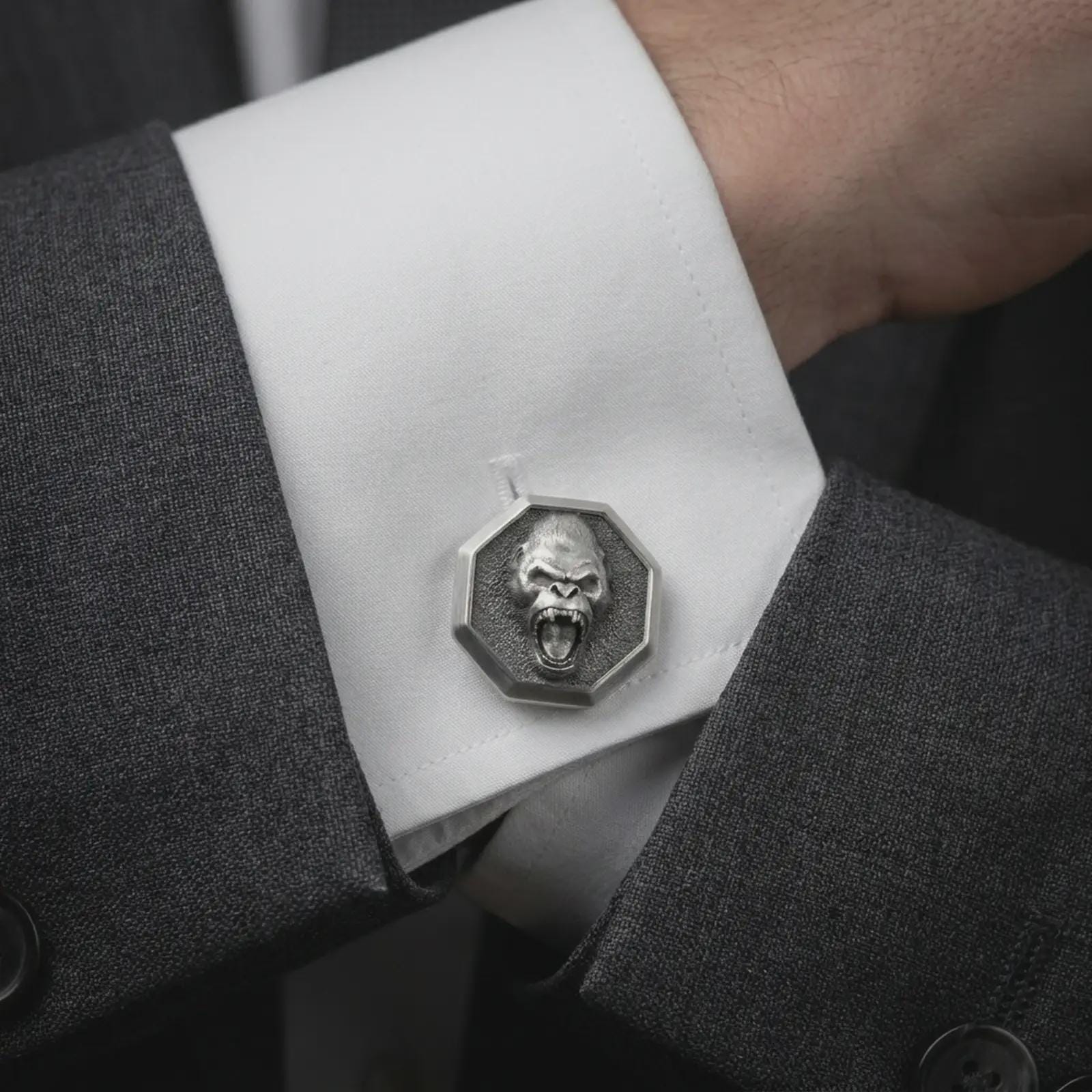 Oxidized gorilla cufflinks worn on a suit cuff, close-up lifestyle jewelry photo showing the roaring ape design with dark formal fabric.