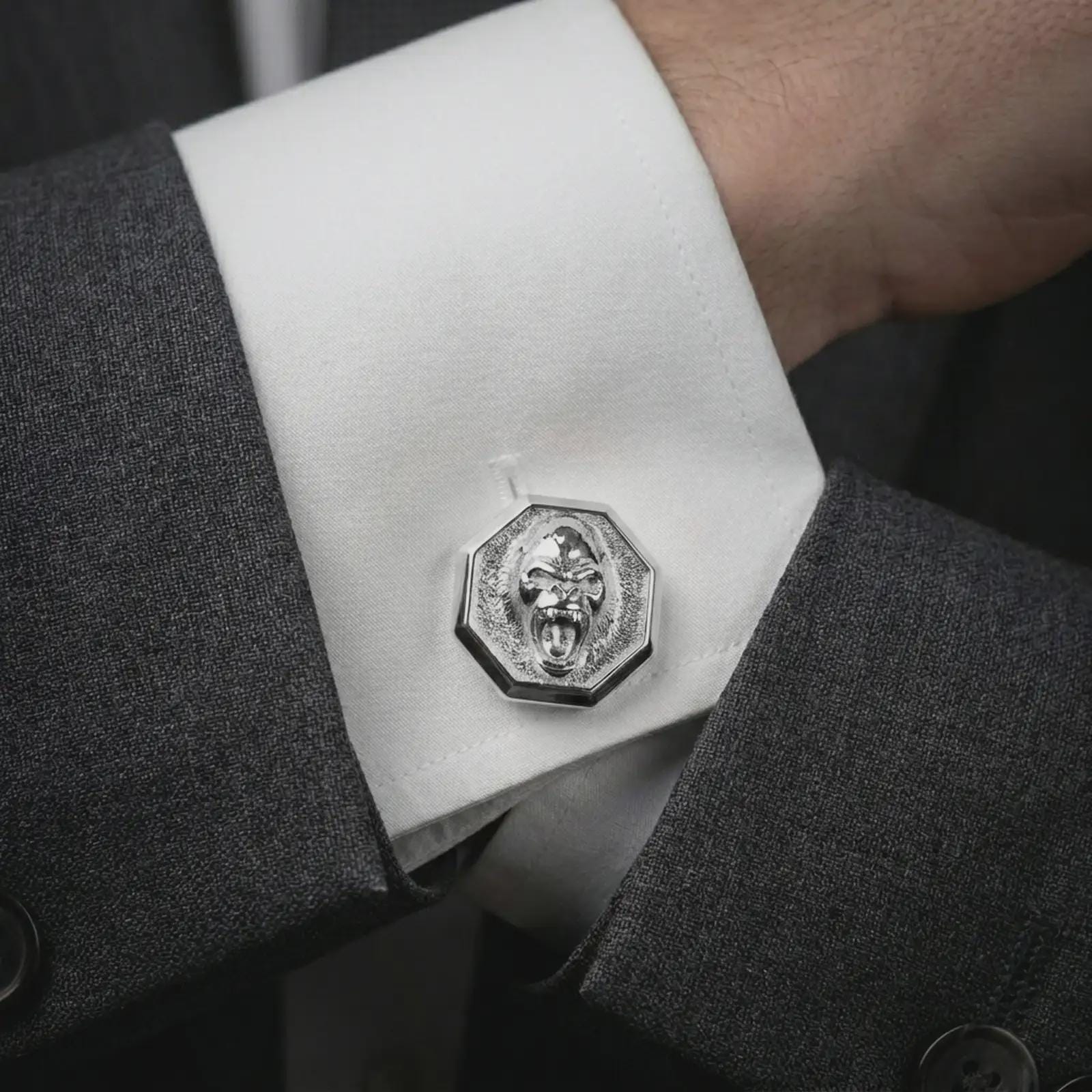 Polished silver gorilla cufflinks worn on a suit cuff, masculine lifestyle shot highlighting the bright silver finish, octagonal frame, and sculpted primate relief.