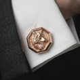 Load image into Gallery viewer, A rose gold plated wolf head cufflink is worn on a shirt cuff in a close-up lifestyle composition, highlighting its octagon frame and sculpted wolf design.

