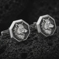 Load image into Gallery viewer, An oxidized wolf head cufflink pair rests on dark volcanic rock in a macro studio close-up, showing sculpted animal detail inside octagon frames.
