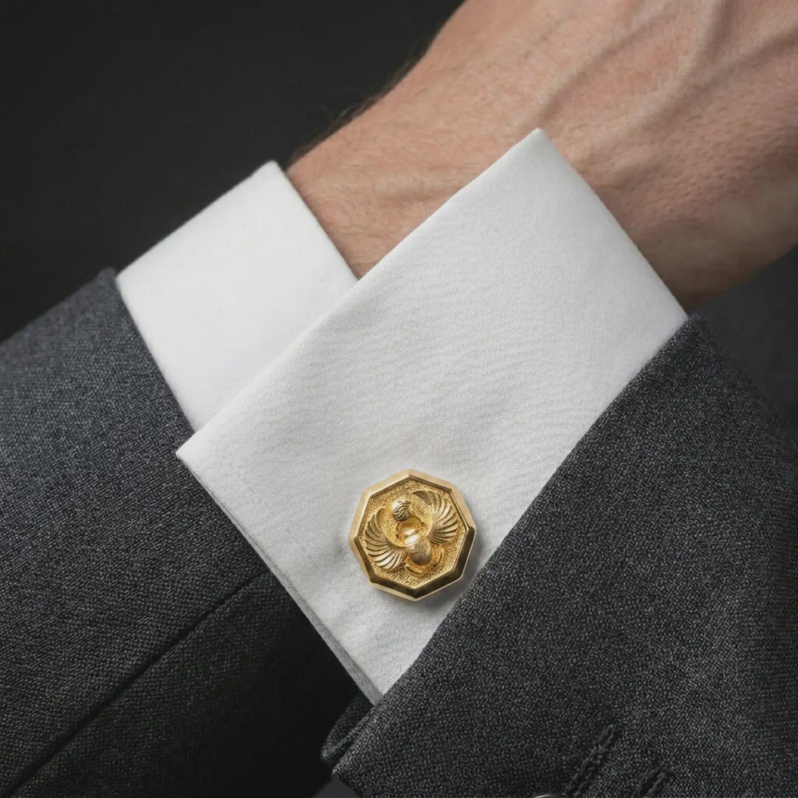 A gold plated scarab cufflink is worn on a white cuff in a close-up lifestyle shot, styled as a meaningful ancient Egyptian gift for men.