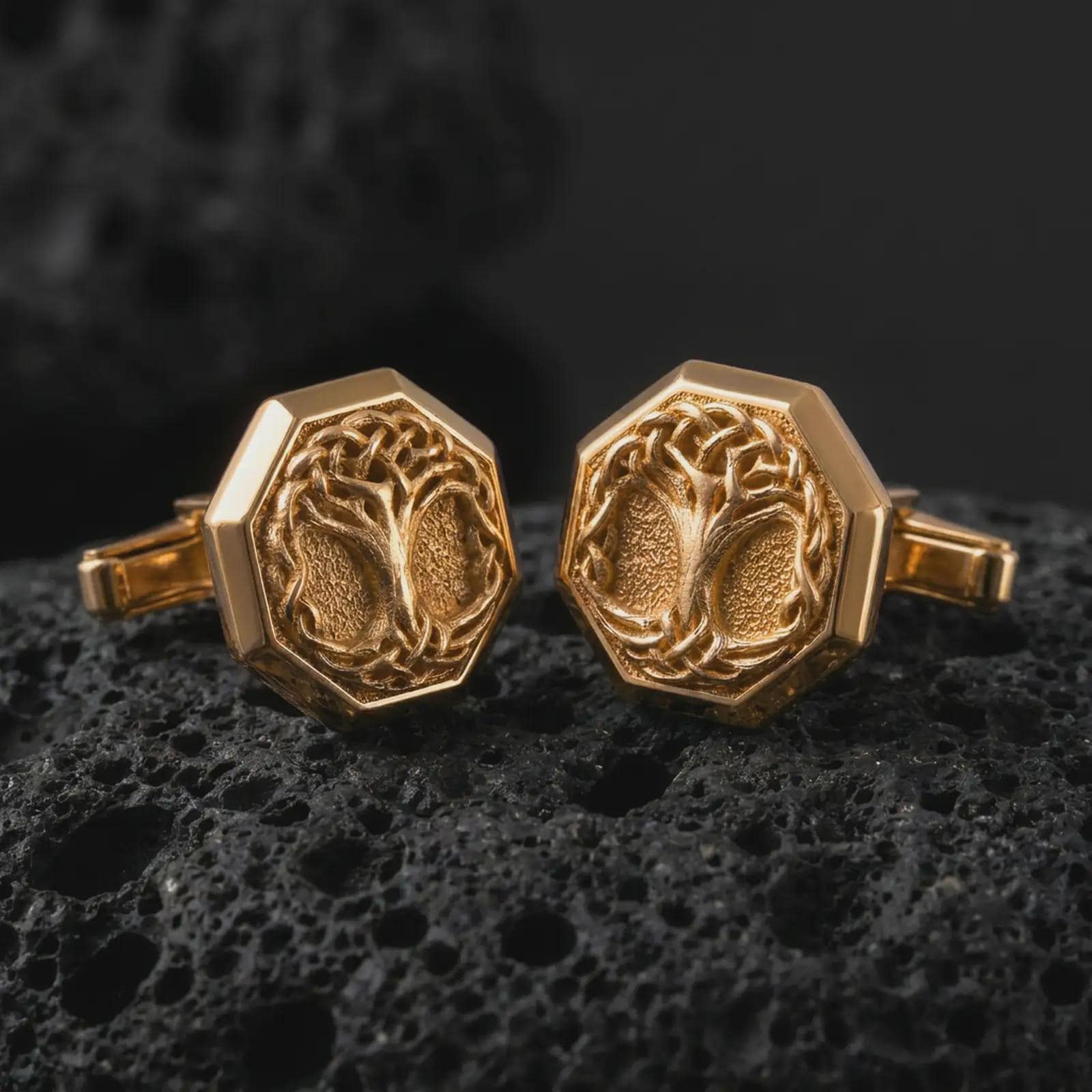 Gold plated Yggdrasil cufflinks sit on textured volcanic rock in a dramatic studio macro shot, highlighting the Viking Tree of Life motif and formal accessory design.