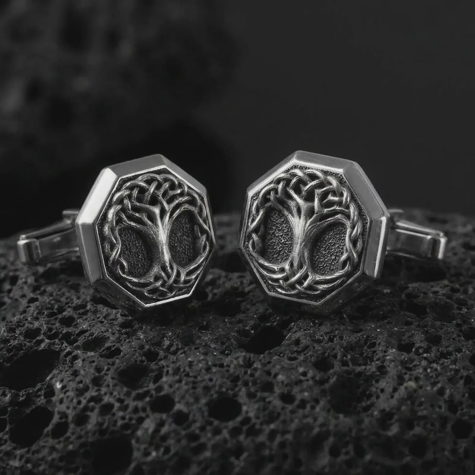 An oxidized Yggdrasil cufflink pair rests on dark volcanic rock in a macro studio close-up, showing a woven Tree of Life design inside octagon frames.