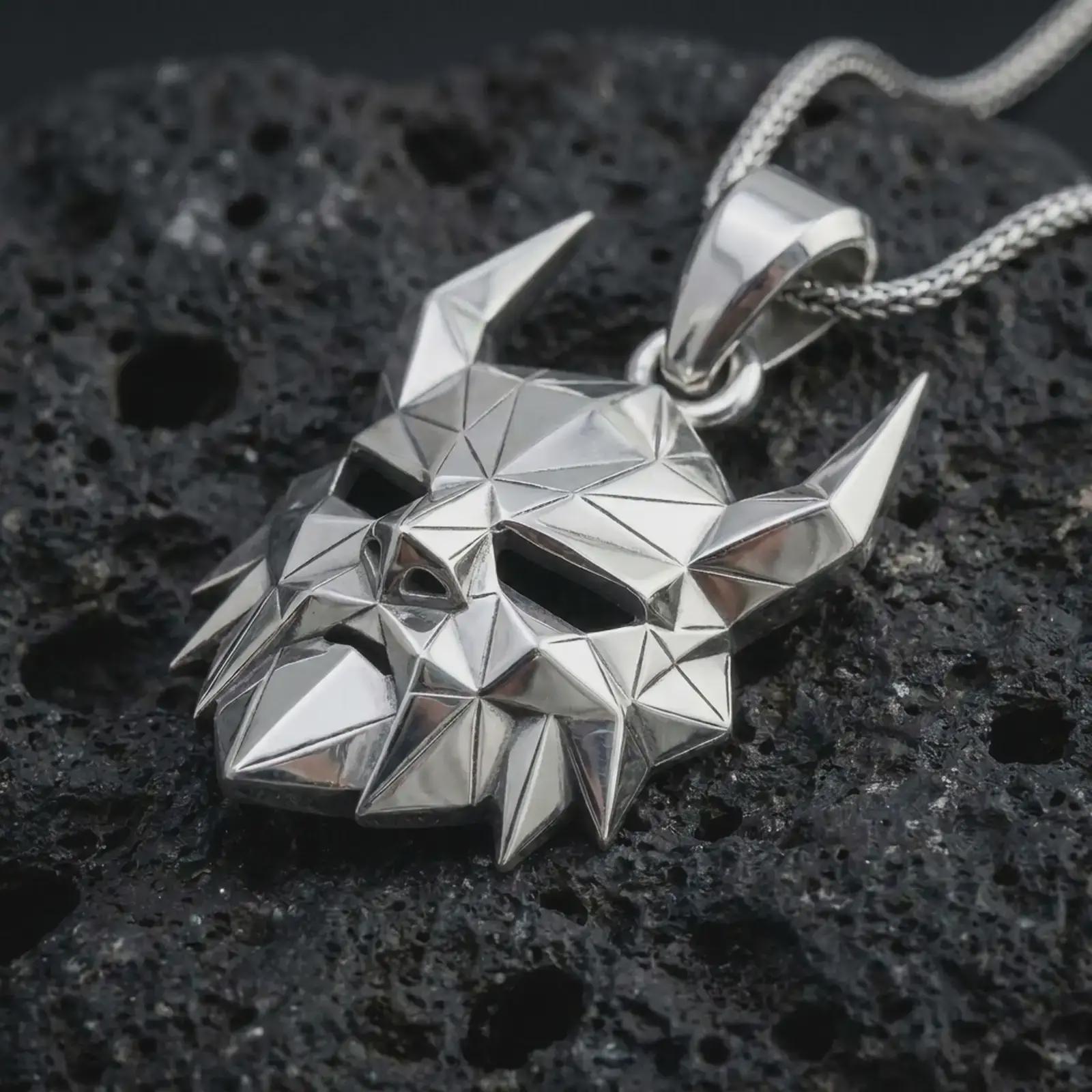 A polished silver Surtur pendant is displayed on black volcanic rock in a premium macro studio close-up with geometric planes and a bold fire giant design.