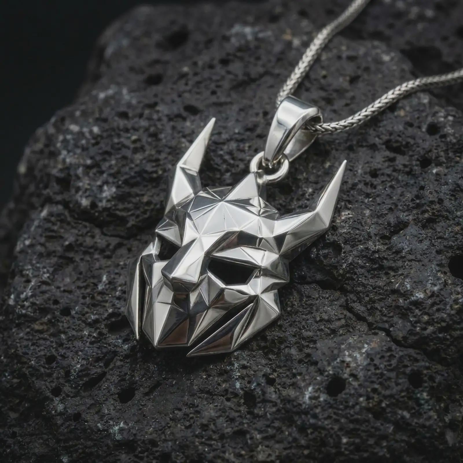 A polished silver Loki pendant is displayed on black volcanic rock in a premium macro studio close-up with sharp geometric planes and bold mask detail.
