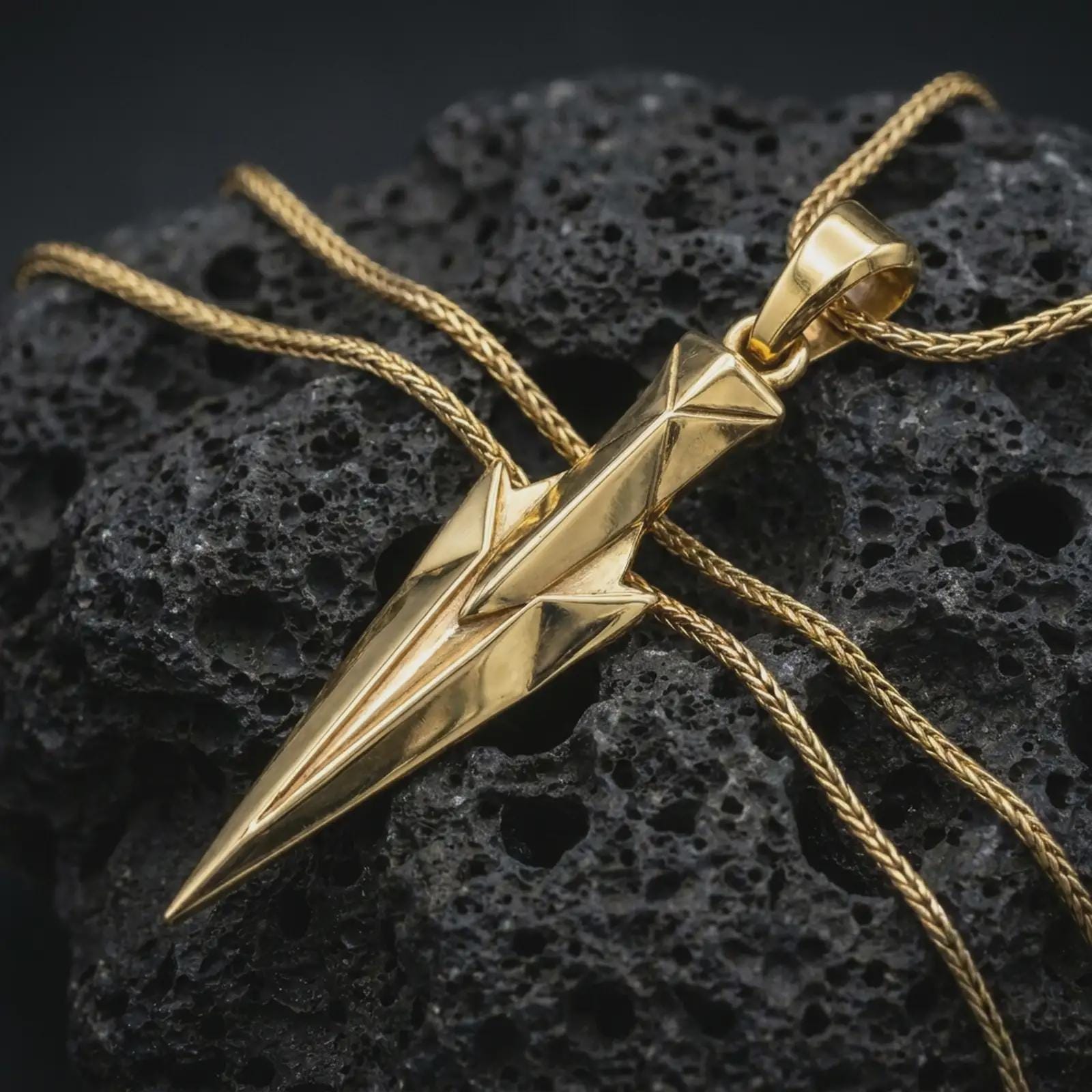 A gold plated Gungnir pendant lies on textured volcanic rock in a dramatic studio macro shot, highlighting the Spear of Odin motif and Viking-inspired form.