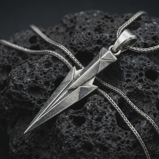 An oxidized Gungnir pendant rests on dark volcanic rock in a macro studio close-up, showing Odin’s spear in a sharp geometric Norse design.