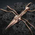 Load image into Gallery viewer, A rose gold plated Gungnir pendant is photographed on porous volcanic rock in a close-up studio composition with refined luxury lighting and faceted sculptural detail.
