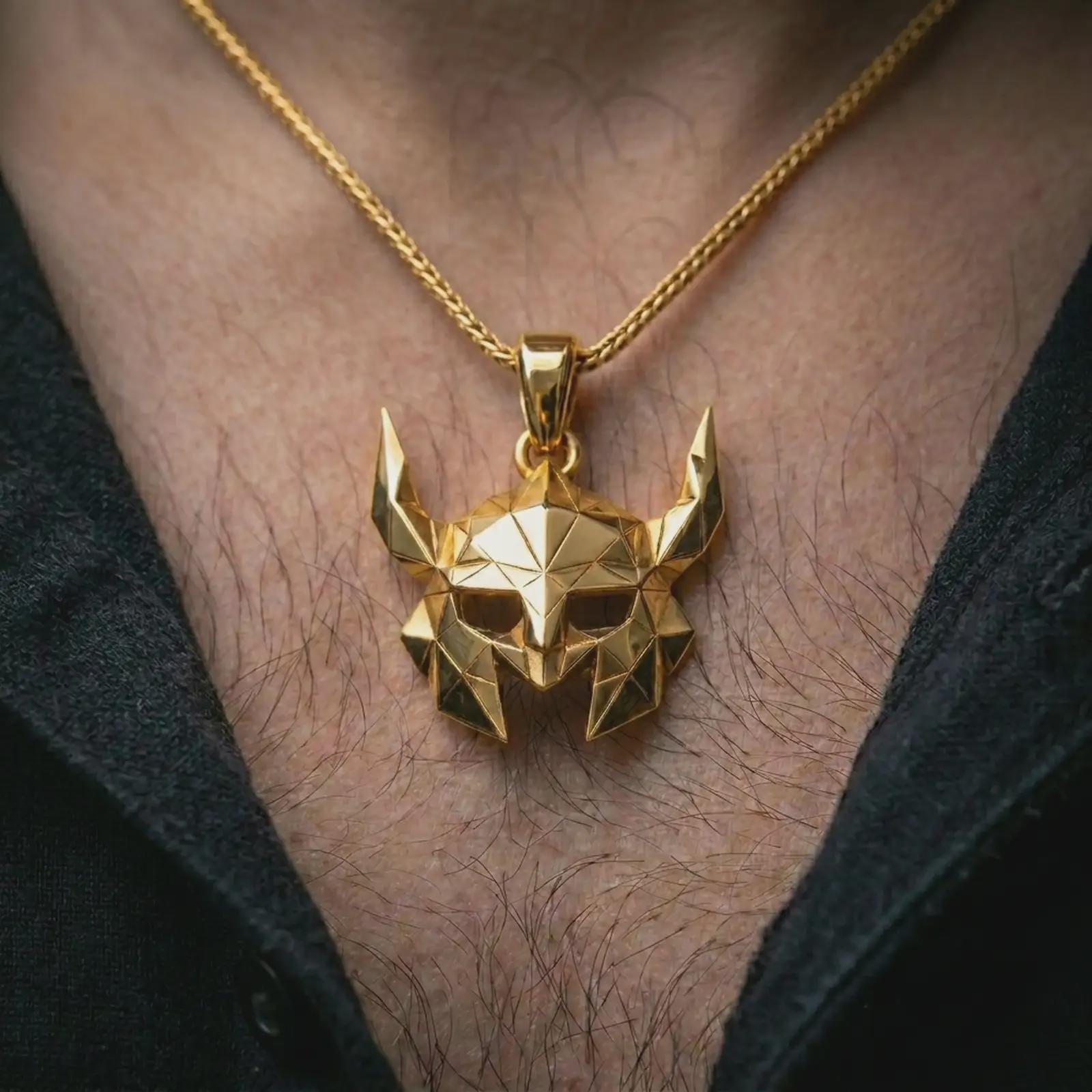 A gold plated Helm of Awe inspired mask pendant is worn on the neck in a close-up lifestyle shot, styled as a meaningful Viking protection gift for men.
