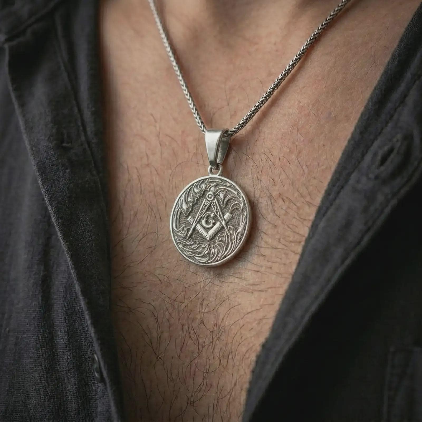 Oxidized Masonic square and compass pendant necklace worn on the chest, close-up lifestyle jewelry photo showing the Freemason medallion on a spiga chain with dark clothing.