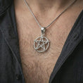 Load image into Gallery viewer, Polished silver thorn pentagram pendant necklace worn on the chest, masculine lifestyle shot highlighting the bright silver finish, thorn-wrapped star, and openwork silhouette.
