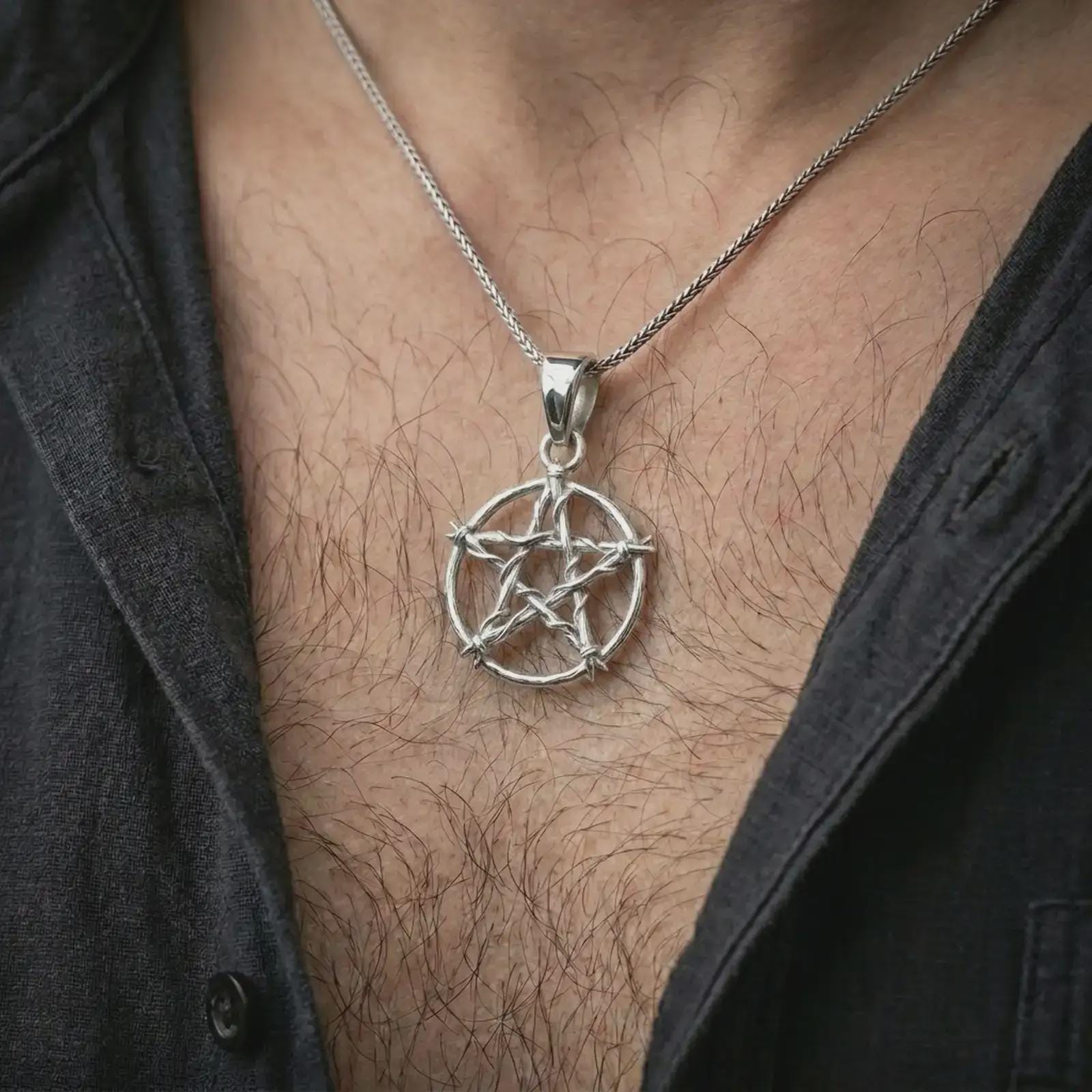 Polished silver thorn pentagram pendant necklace worn on the chest, masculine lifestyle shot highlighting the bright silver finish, thorn-wrapped star, and openwork silhouette.