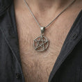 Load image into Gallery viewer, Oxidized thorn pentagram pendant necklace worn on the chest, close-up lifestyle jewelry photo showing the gothic star talisman on a spiga chain with dark clothing.
