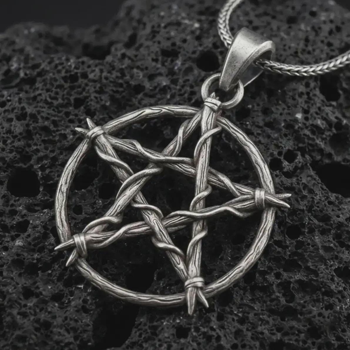 Oxidized thorn pentagram pendant necklace on textured volcanic rock, close-up studio shot highlighting the woven thorn circle, five-point star shape, barbed details, and antique silver contrast.