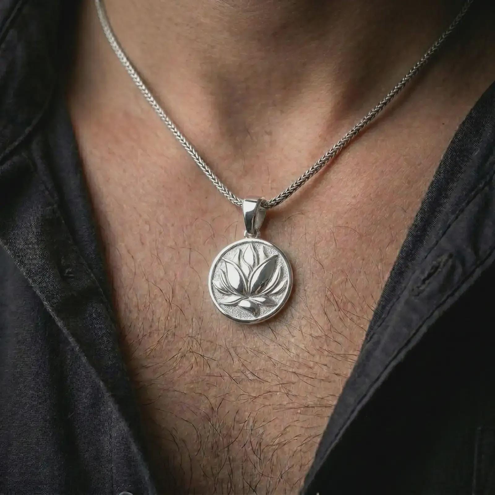 Polished silver lotus flower pendant necklace worn on the chest, feminine lifestyle shot highlighting the bright silver finish, layered petals, and peaceful floral relief.