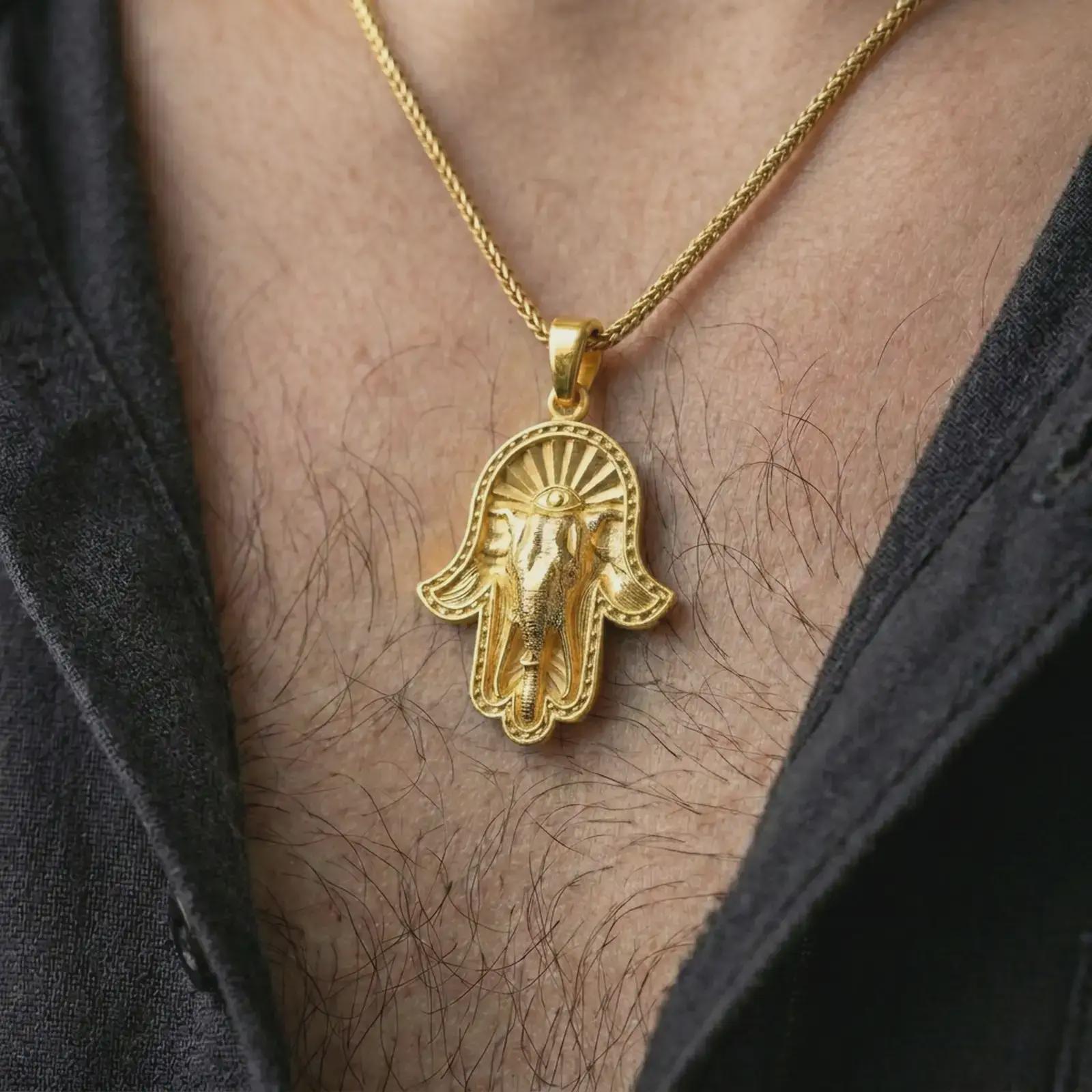 Gold plated hamsa elephant pendant necklace worn on the chest, premium lifestyle jewelry photo with the hamsa elephant pendant centered on a spiga chain.