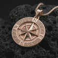 Load image into Gallery viewer, Rose gold plated Greek compass pendant necklace on textured volcanic rock, detailed macro product shot with soft warm reflections and symbolic journey-inspired styling.
