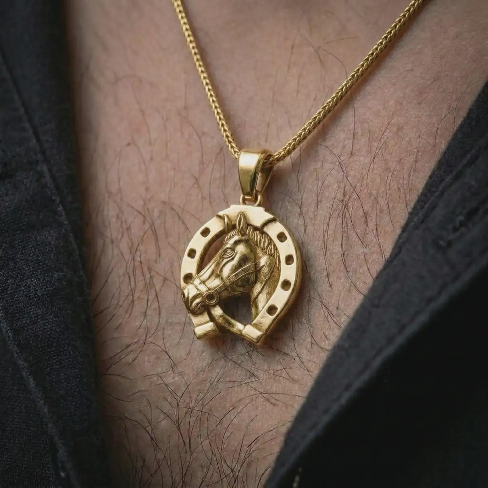 Gold plated horseshoe pendant necklace worn on the chest, premium lifestyle jewelry photo with the good luck horse pendant centered on a spiga chain.