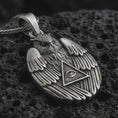 Load image into Gallery viewer, Oxidized owl all-seeing eye pendant necklace on textured volcanic rock, close-up studio shot highlighting the winged owl relief, triangle eye symbol, feather details, and antique silver contrast.
