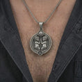 Load image into Gallery viewer, Oxidized Gemini zodiac pendant necklace worn on the chest, close-up lifestyle jewelry photo showing the twins astrology medallion on a spiga chain with dark clothing.
