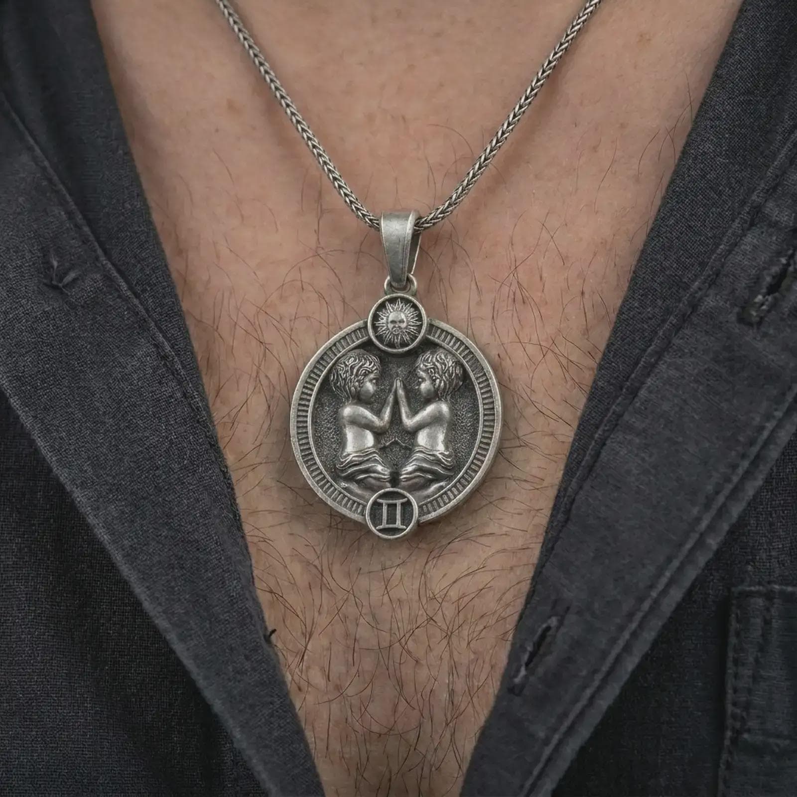 Oxidized Gemini zodiac pendant necklace worn on the chest, close-up lifestyle jewelry photo showing the twins astrology medallion on a spiga chain with dark clothing.
