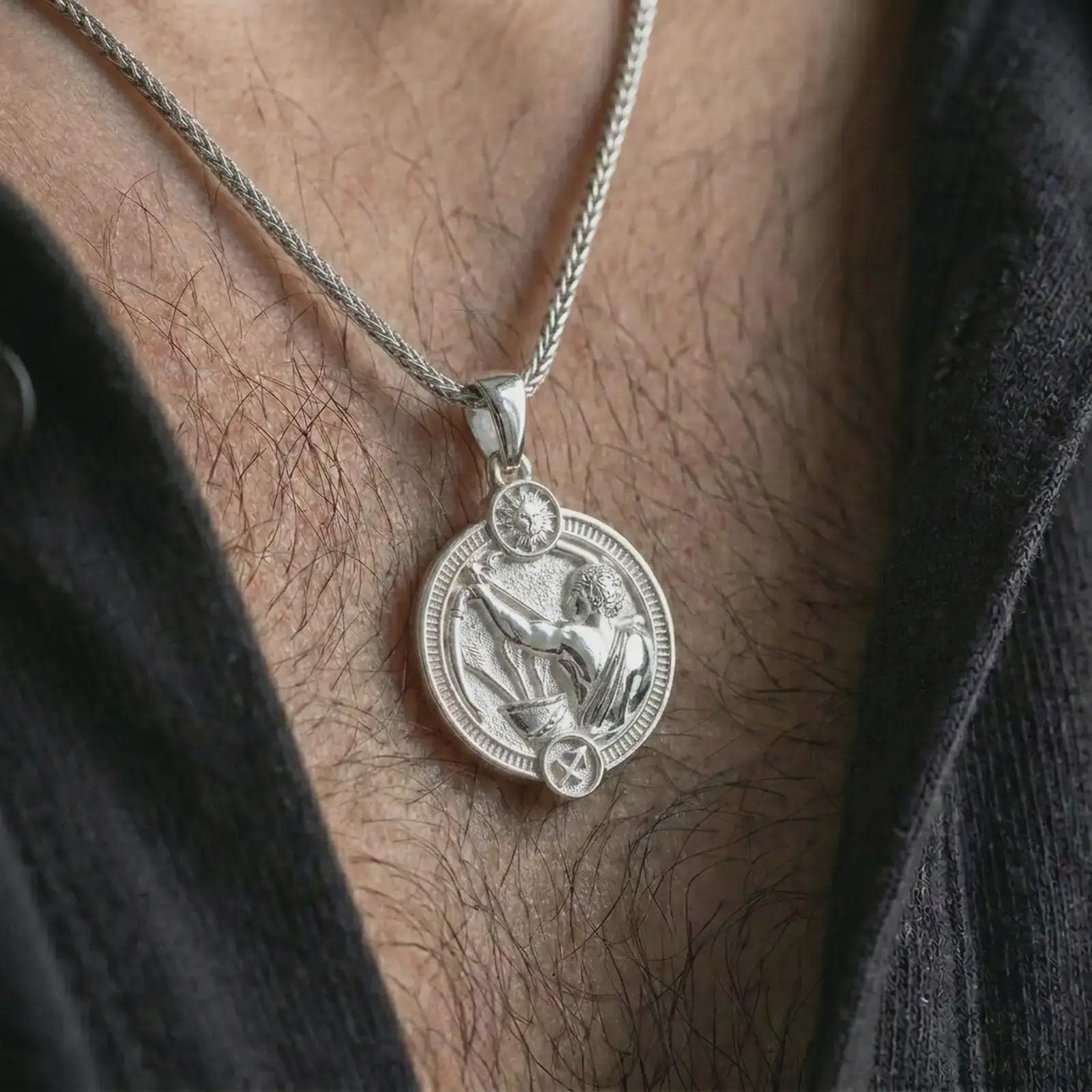 Polished silver Sagittarius zodiac pendant necklace worn on the chest, masculine lifestyle shot highlighting the bow and arrow relief, sun detail, and bright silver finish.